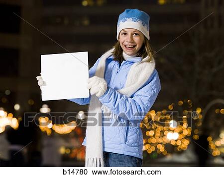 Stock Image - Girl with braces outdoors in winter with blank sign. Fotosearch