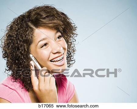Stock Photography - Girl with braces talking on cell phone smiling. Fotosearch