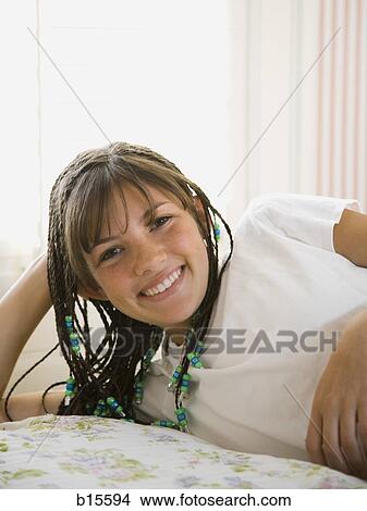 Girl with braids lying down on bed smiling View Large Photo Image Picture - Girl with braids lying down on bed smiling. Fotosearch