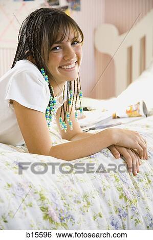 Girl with braids lying down on bed smiling View Large Photo Image Stock Photograph - Girl with braids lying down on bed smiling. Fotosearch