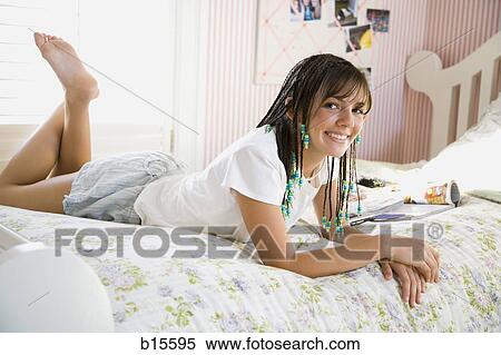 Girl with braids lying down on bed smiling View Large Photo Image Stock Photography - Girl with braids lying down on bed smiling. Fotosearch