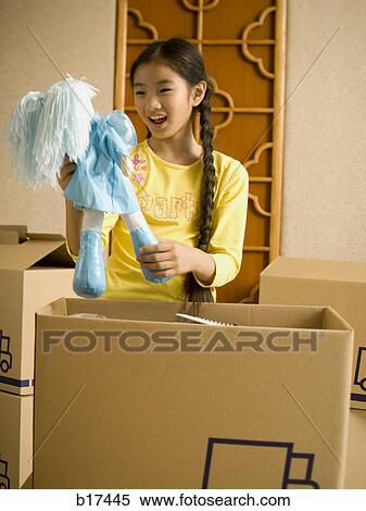 Girl with cardboard boxes holding doll smiling View Large Photo Image Stock Photography - Girl with cardboard boxes holding doll smiling. Fotosearch