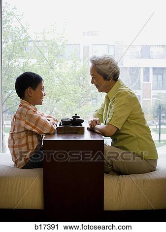 Grandmother and grandson sitting cross legged drinking tea View Large Photo Image Stock Image - Grandmother and grandson sitting cross legged drinking tea. Fotosearch