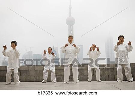 Stock Photography - Group doing tai chi outdoors with city skyline in background. Fotosearch