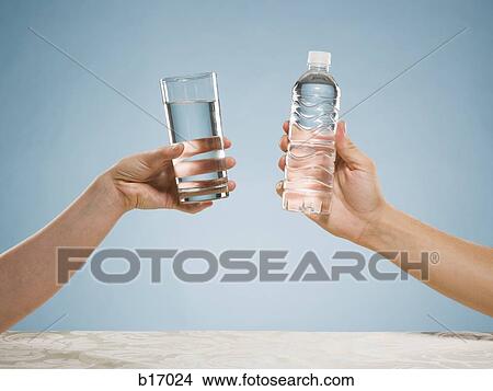 Hand holding glass of water and hand holding bottled water View Large Photo Image Picture - Hand holding glass of water and hand holding bottled water. Fotosearch