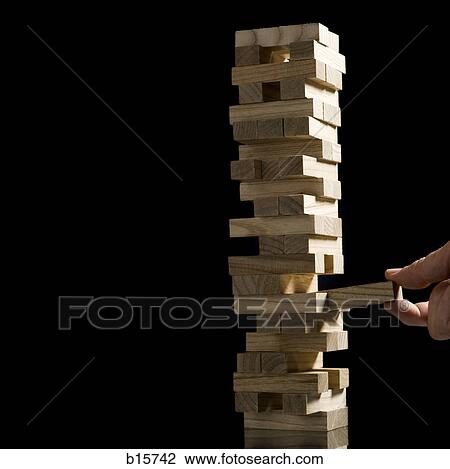 Hand removing block from stack of wooden blocks View Large Photo Image Stock Image - Hand removing block from stack of wooden blocks. Fotosearch