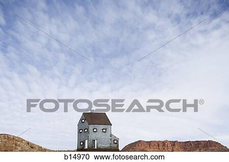Stock Image - House with red rock and blue sky with clouds. Fotosearch