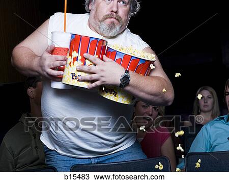 Large man with buckets of popcorn and drink at movie theater View Large Photo Image Stock Image - Large man with buckets of popcorn and drink at movie theater. Fotosearch