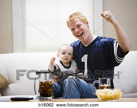 Man and baby on sofa cheering View Large Photo Image Stock Image - Man and baby on sofa cheering. Fotosearch