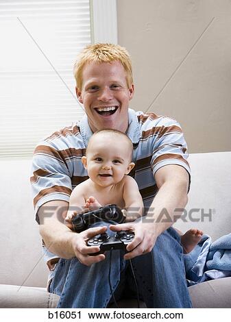 Man and baby on sofa with video game controller smiling View Large Photo Image Stock Image - Man and baby on sofa with video game controller smiling. Fotosearch