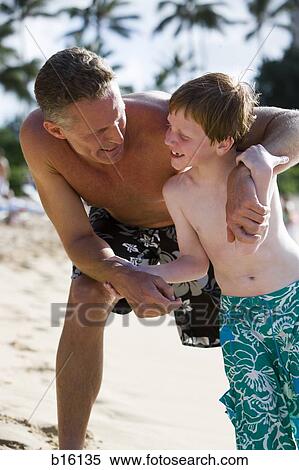 Man and boy on beach in swimming trunks View Large Photo Image Stock Photography - Man and boy on beach in swimming trunks. Fotosearch