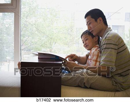 Man and boy sitting and reading in front of large window View Large Photo Image Stock Image - Man and boy sitting and reading in front of large window. Fotosearch