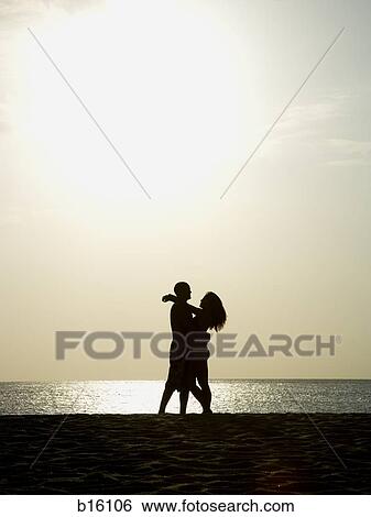 Man and woman embracing at sunset on beach View Large Photo Image Stock Photograph - Man and woman embracing at sunset on beach. Fotosearch