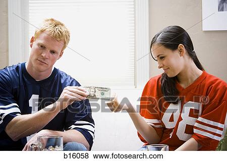 Man and woman in football jerseys handing woman money View Large Photo Image Stock Photo - Man and woman in football jerseys handing woman money. Fotosearch
