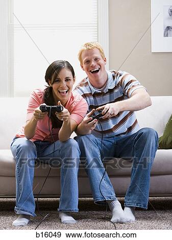 Man and woman sitting on sofa playing video games laughing View Large Photo Image Stock Photo - Man and woman sitting on sofa playing video games laughing. Fotosearch