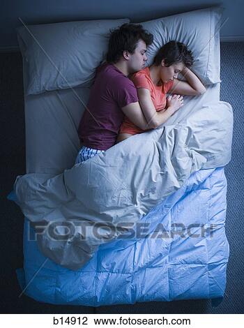 Stock Image - Man and woman snuggling in bed asleep. Fotosearch