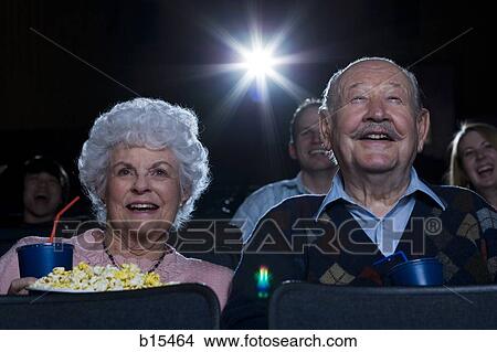 Picture - Man and woman watching film at movie theater smiling. Fotosearch