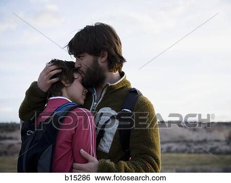 Stock Photograph - Man and woman with backpacks embracing outdoors. Fotosearch