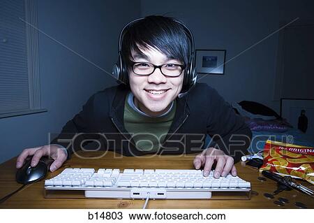 Stock Image - Man at keyboard with headset smiling. Fotosearch