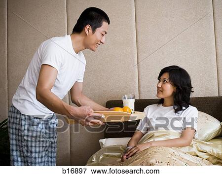 Man bringing woman breakfast in bed View Large Photo Image Stock Photo - Man bringing woman breakfast in bed. Fotosearch