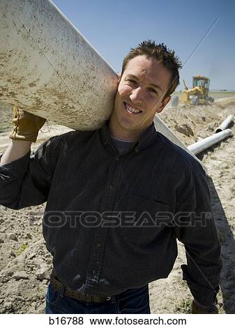 Man carrying pipe outdoors smiling View Large Photo Image Stock Photo - Man carrying pipe outdoors smiling. Fotosearch