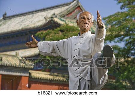 Stock Image - Man doing Kung Fu outdoors with pagoda in background. Fotosearch