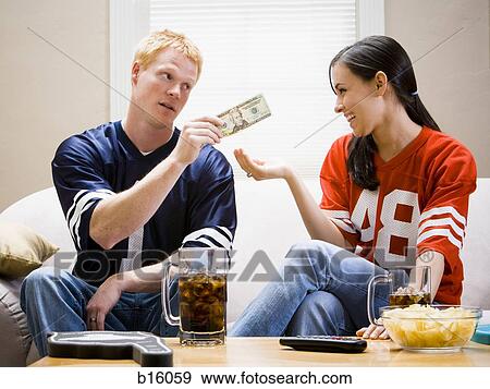 Man giving woman money both in football jerseys View Large Photo Image Stock Photo - Man giving woman money both in football jerseys. Fotosearch