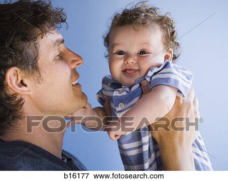 Man holding baby boy smiling View Large Photo Image Stock Photo - Man holding baby boy smiling. Fotosearch