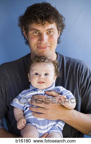 Man holding baby boy square to camera smiling View Large Photo Image Stock Image - Man holding baby boy square to camera smiling. Fotosearch
