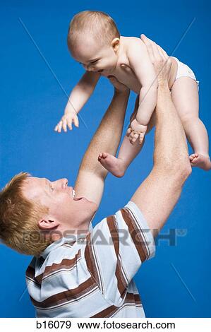 Man holding baby in air smiling View Large Photo Image Stock Photo - Man holding baby in air smiling. Fotosearch