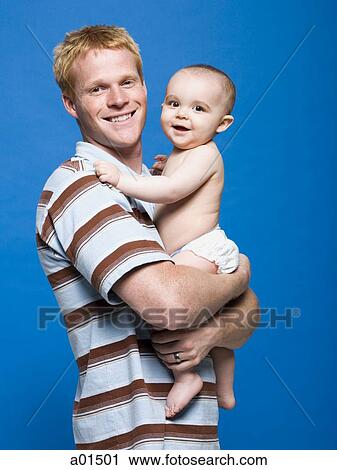Stock Image - Man holding baby smiling. Fotosearch