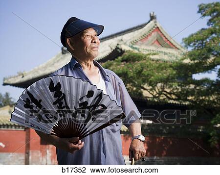 Man holding Chinese fan with pagoda and blue sky in background View Large Photo Image Stock Image - Man holding Chinese fan with pagoda and blue sky in background. Fotosearch
