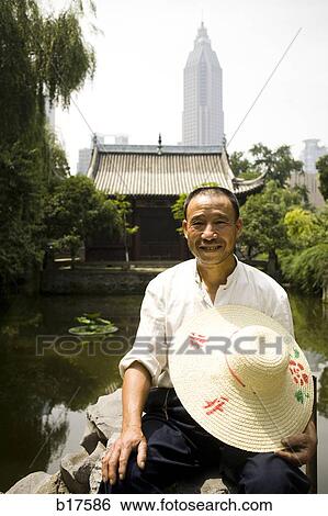 Man holding straw hat with city skyline in background View Large Photo Image Stock Photograph - Man holding straw hat with city skyline in background. Fotosearch