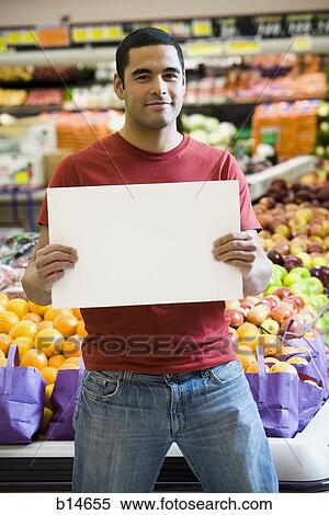 Man in grocery store holding blank sign View Large Photo Image Stock Photography - Man in grocery store holding blank sign. Fotosearch