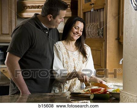 Man in kitchen with woman chopping vegetables smiling View Large Photo Image Stock Photo - Man in kitchen with woman chopping vegetables smiling. Fotosearch