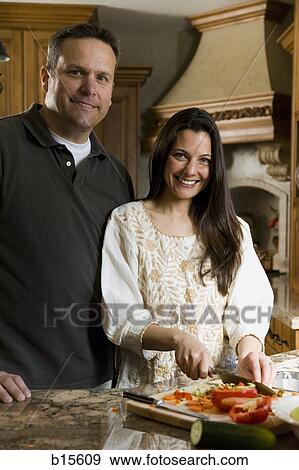 Man in kitchen with woman chopping vegetables smiling View Large Photo Image Stock Photo - Man in kitchen with woman chopping vegetables smiling. Fotosearch