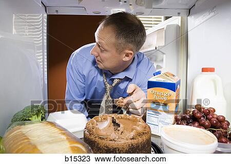 Man in refrigerator taking icing from chocolate cake View Large Photo Image Stock Image - Man in refrigerator taking icing from chocolate cake. Fotosearch