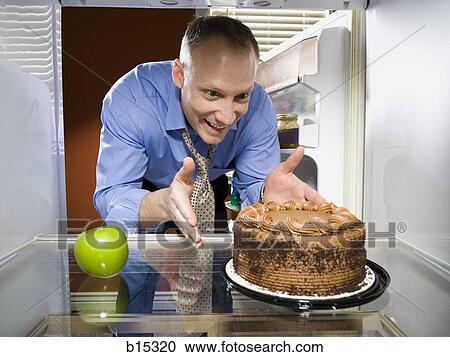 Man in refrigerator with green apple reaching for chocolate cake View Large Photo Image Stock Image - Man in refrigerator with green apple reaching for chocolate cake. Fotosearch