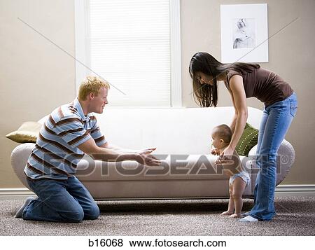 Man kneeling and woman teaching baby to walk View Large Photo Image Stock Photo - Man kneeling and woman teaching baby to walk. Fotosearch