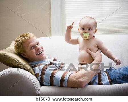 Man lying down on sofa with baby View Large Photo Image Stock Image - Man lying down on sofa with baby. Fotosearch