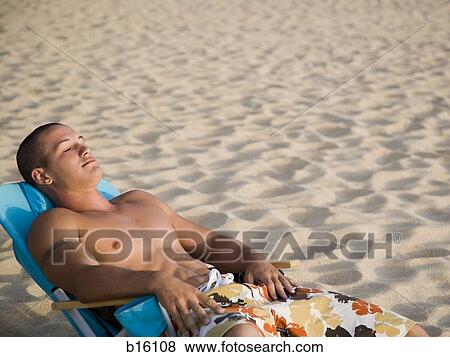 Man lying in chair on sandy beach View Large Photo Image Stock Photo - Man lying in chair on sandy beach. Fotosearch
