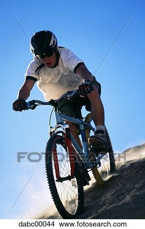 Man riding mountain bike with helmet and blue sky View Large Photo Image Picture - Man riding mountain bike with helmet and blue sky. Fotosearch