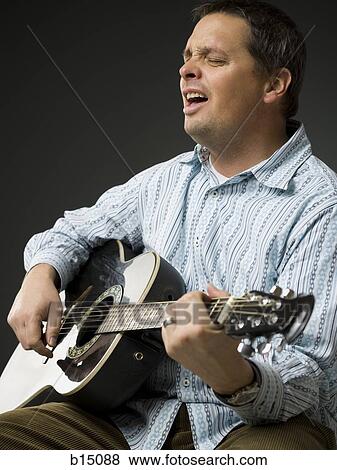 Man singing and playing guitar with eyes closed View Large Photo Image Stock Photo - Man singing and playing guitar with eyes closed. Fotosearch