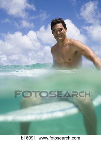 Man sitting on surfboard in water smiling View Large Photo Image Stock Image - Man sitting on surfboard in water smiling. Fotosearch