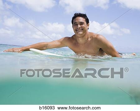 Man sitting on surfboard in water smiling View Large Photo Image Stock Image - Man sitting on surfboard in water smiling. Fotosearch