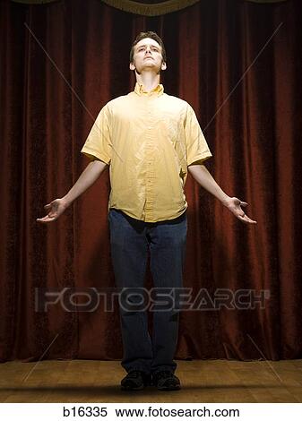 Stock Photography - Man standing on stage with arms open. Fotosearch