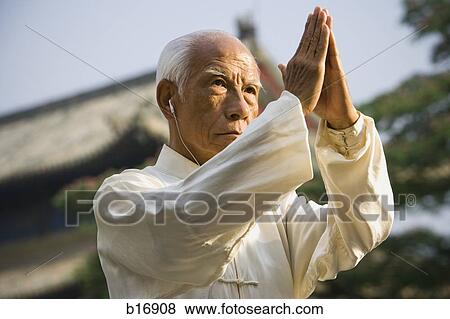 Man standing outdoors doing Kung Fu with ear buds and pagoda in background View Large Photo Image Stock Photo - Man standing outdoors doing Kung Fu with ear buds and pagoda in background. Fotosearch