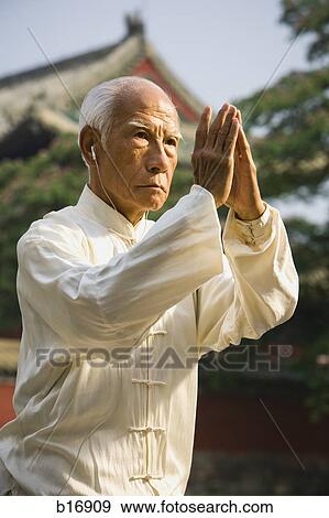 Man standing outdoors doing Kung Fu with ear buds and pagoda in background View Large Photo Image Stock Photo - Man standing outdoors doing Kung Fu with ear buds and pagoda in background. Fotosearch