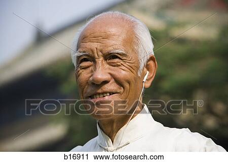 Man standing outdoors with ear buds smiling View Large Photo Image Stock Image - Man standing outdoors with ear buds smiling. Fotosearch