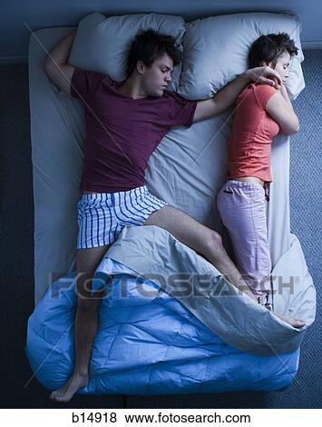 Man stretched out on bed with woman sleeping View Large Photo Image Stock Photo - Man stretched out on bed with woman sleeping. Fotosearch